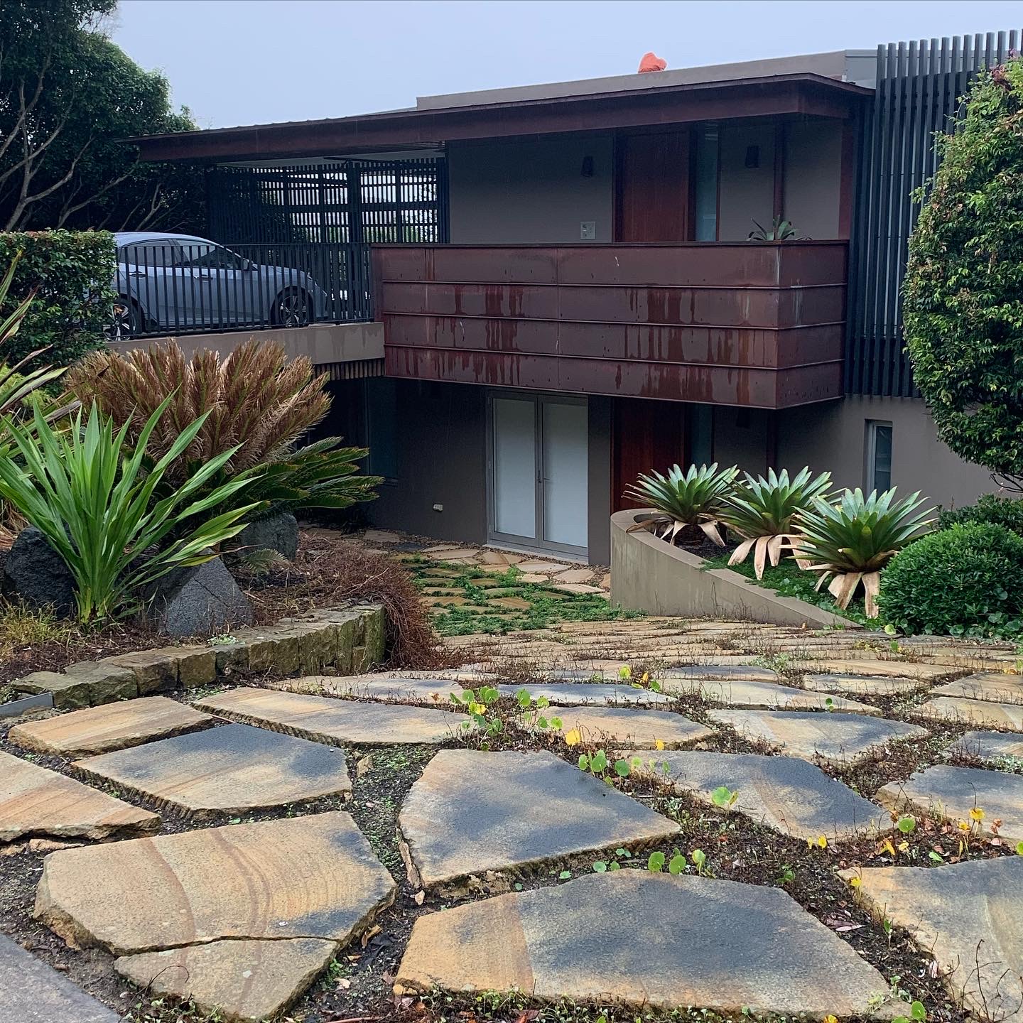 Sandstone patio on Sydney’s Northern Beaches covered in black mould and organic build-up before cleaning